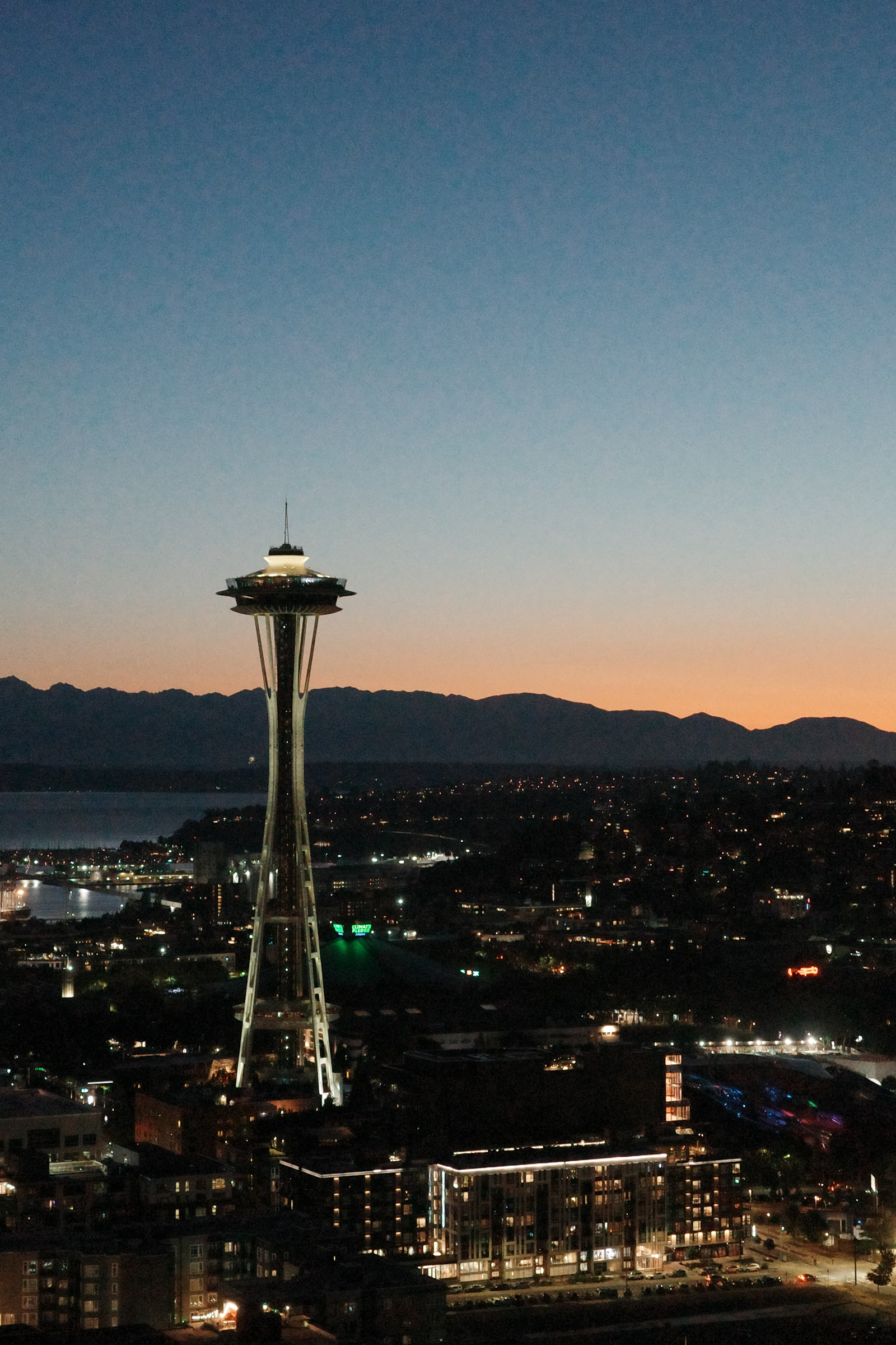 The Space Needle at dusk with the Olympic Mountains behind it